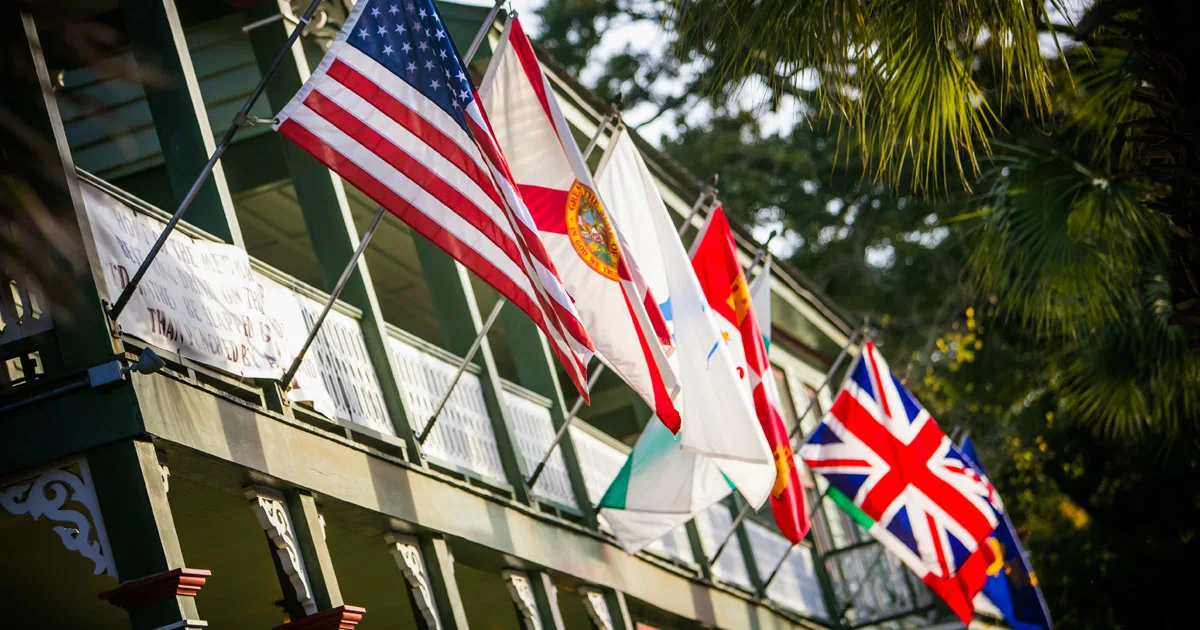 A row of historic flags, including the United States, Florida and Union Jack, lining a veranda on Amelia Island.